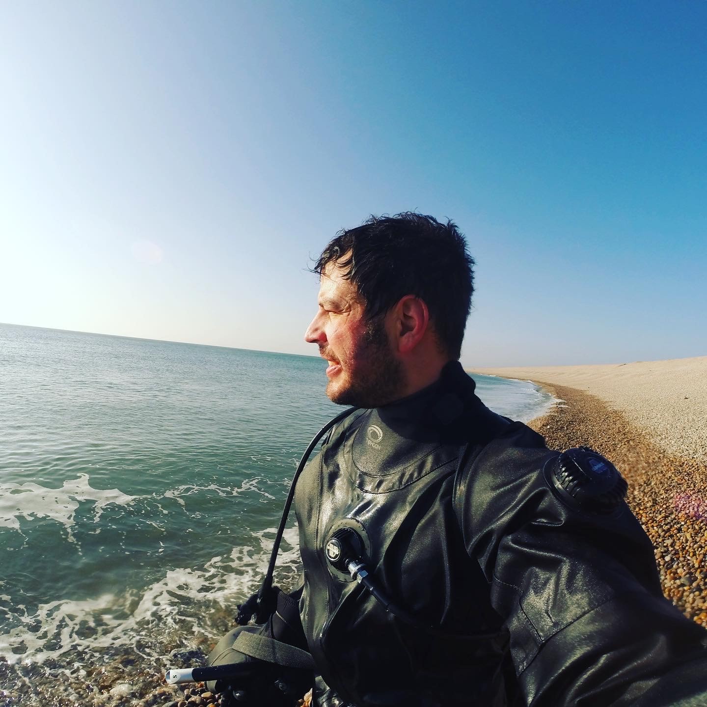 Image of a diver on a beach wearing his Divesuit.